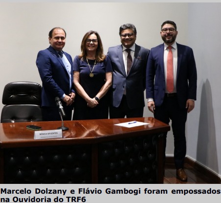 Fotografia horizontal colorida pessoas em pé atrás da mesa. Legenda: Marcelo Dolzany e Flávio Gambogi foram empossados na Ouvidoria do TRF6.