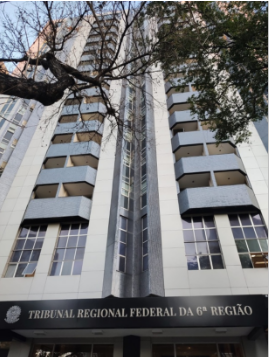 Fotografia vertical e colorida de um prédio com muitos andares. Embaixo, lê-se: "Tribunal Regional Federal da 6ª Região".