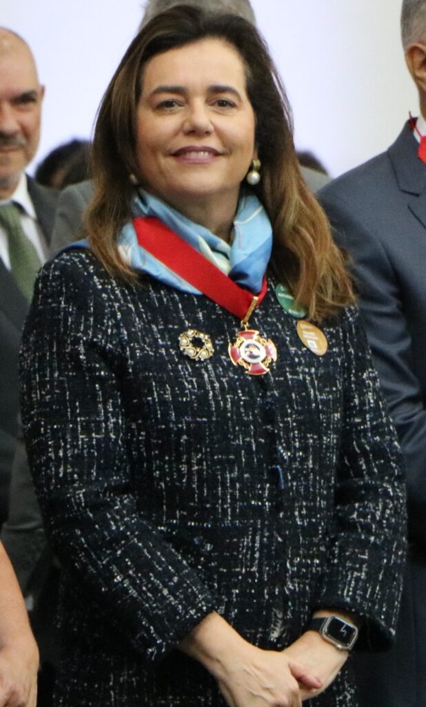 Fotografia vertical de uma mulher com uma medalha ao redor do pescoço. Legenda: Presidente do TRF6, desembargadora federal Mônica Sifuentes, recebe a Grande Medalha