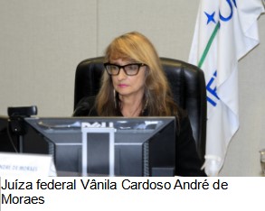 Foto colorida horizontal da juíza federal Vânila Cardoso sentada em frente a um computador no auditório da reunião.