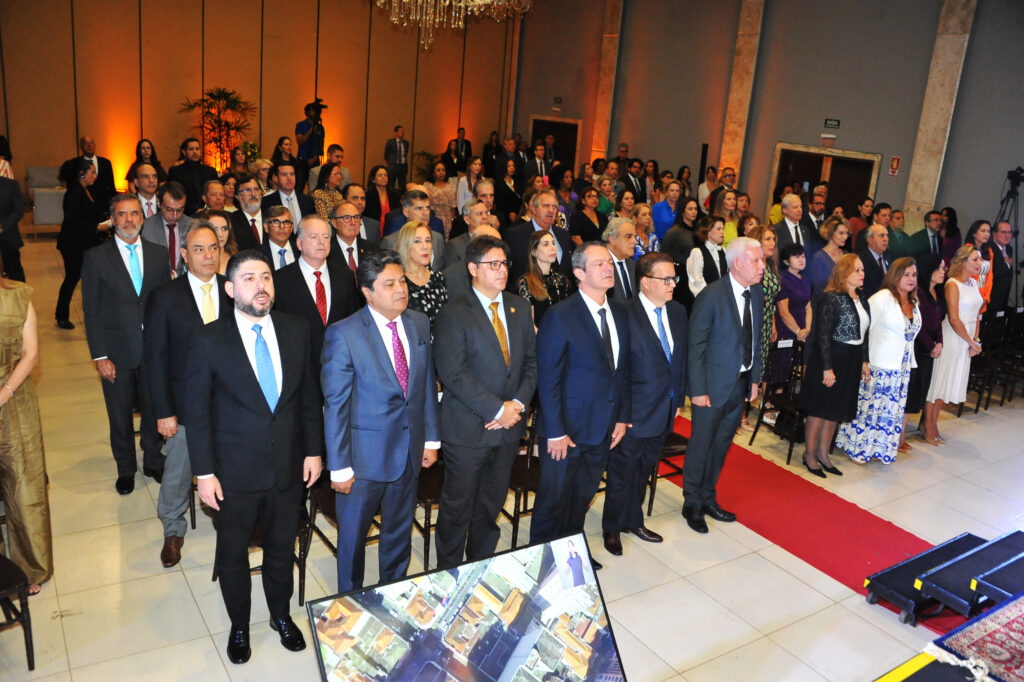 Fotografia retangular e colorida em que aparecem vários homens de terno e gravata