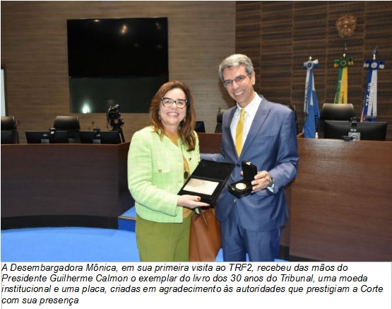 Foto retangular colorida: Desembargadora Mônica Sifuentes recebe placa e medalha do desembargador Guilherme Calmon. Os dois sorriem para a câmera.