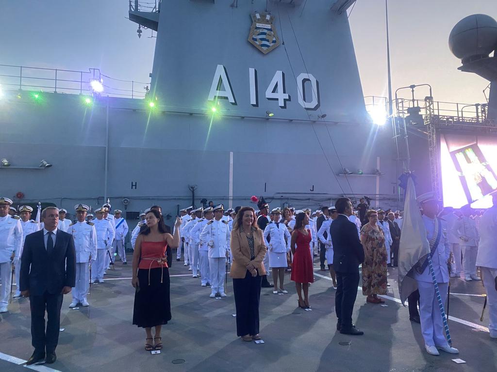 Fotografia colorida de várias pessoas das forças armadas, do poder executivo e do judiciário perfilados em um navio da Marinha.