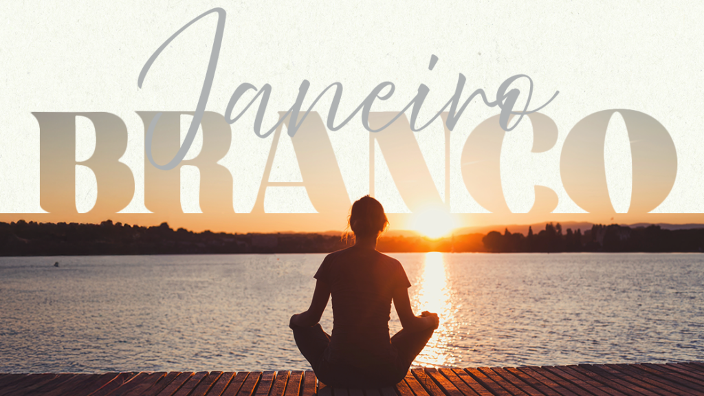 A imagem apresenta o título "Janeiro Branco" com um design limpo e delicado. No centro, vemos uma mulher de costas, sentada na posição de meditação, contemplando um nascer ou pôr do sol sobre um lago. O cenário transmite serenidade e calma, reforçando a mensagem de reflexão e cuidado com a saúde mental, que é o foco da campanha Janeiro Branco. O texto utiliza fontes estilizadas, e a composição tem tons claros que evocam tranquilidade e equilíbrio emocional.