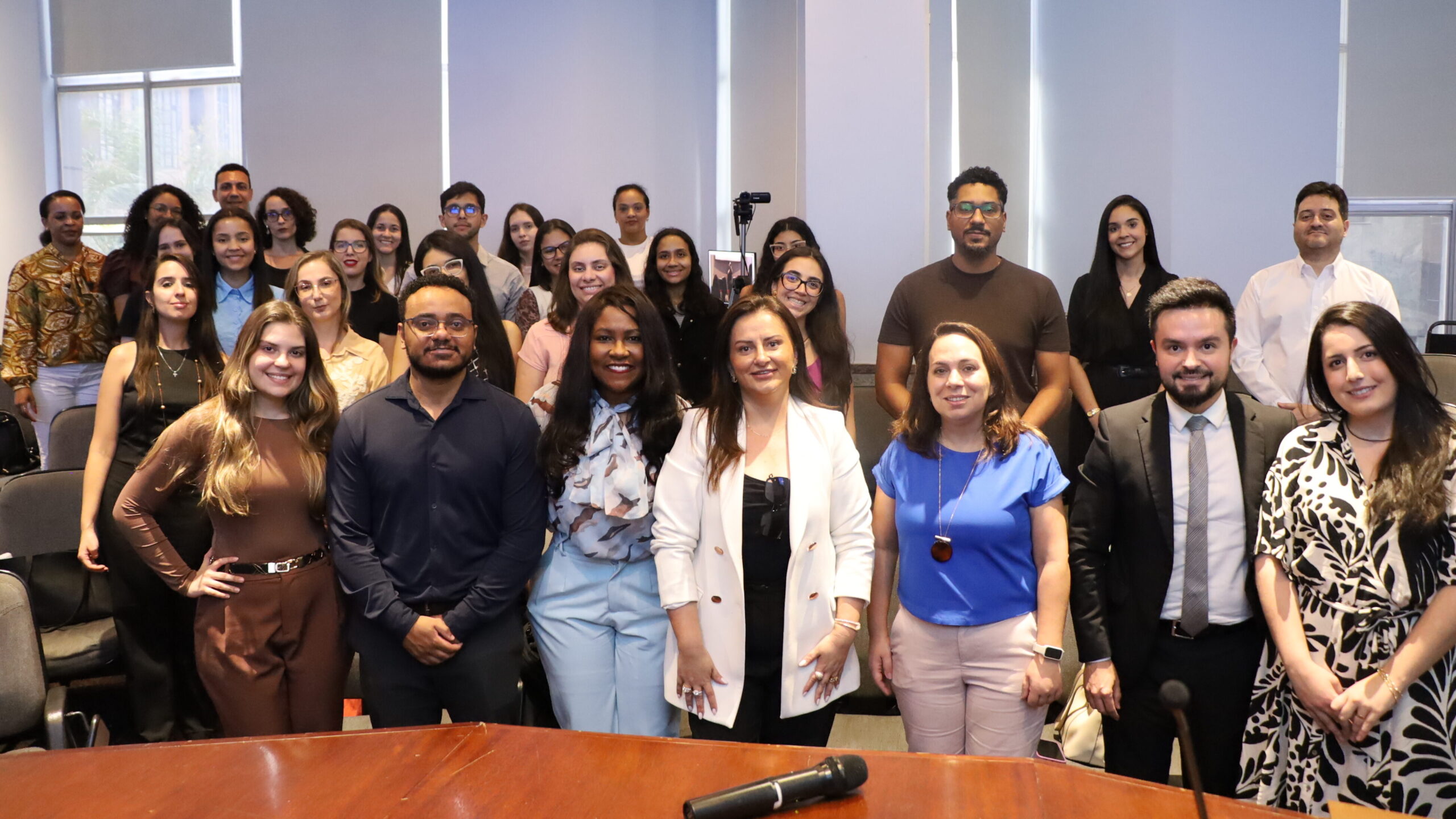 A imagem é uma fotografia de um grupo de pessoas, composto por homens e mulheres, de pé e posando para a câmera.