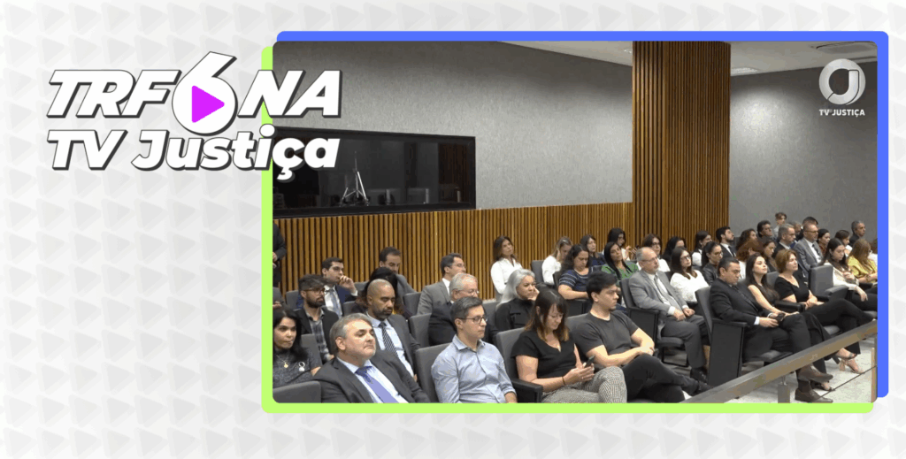 A imagem é uma captura de tela de uma transmissão da TV Justiça, com o título "TRF6 NA TV Justiça". O quadro principal da tela mostra um auditório. Várias pessoas estão sentadas em fileiras de cadeiras pretas, voltadas para a frente. O ambiente é bem iluminado e moderno, com painéis de madeira e detalhes em cinza nas paredes.