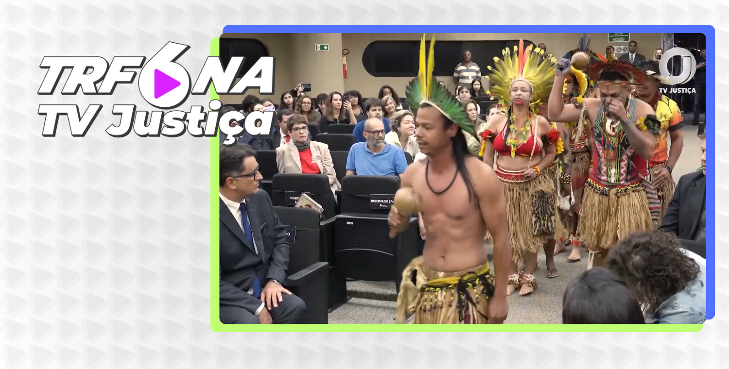Esta é uma captura de tela de vídeo de um evento ou reportagem, com um quadro de destaque à direita. A cena principal mostra um grupo de pessoas vestidas com trajes indígenas tradicionais, incluindo cocares e saias de palha, realizando uma apresentação ou ritual em um auditório, com espectadores sentados ao fundo. No canto superior esquerdo, há um logo com o texto "TRF6 NA TV Justiça".