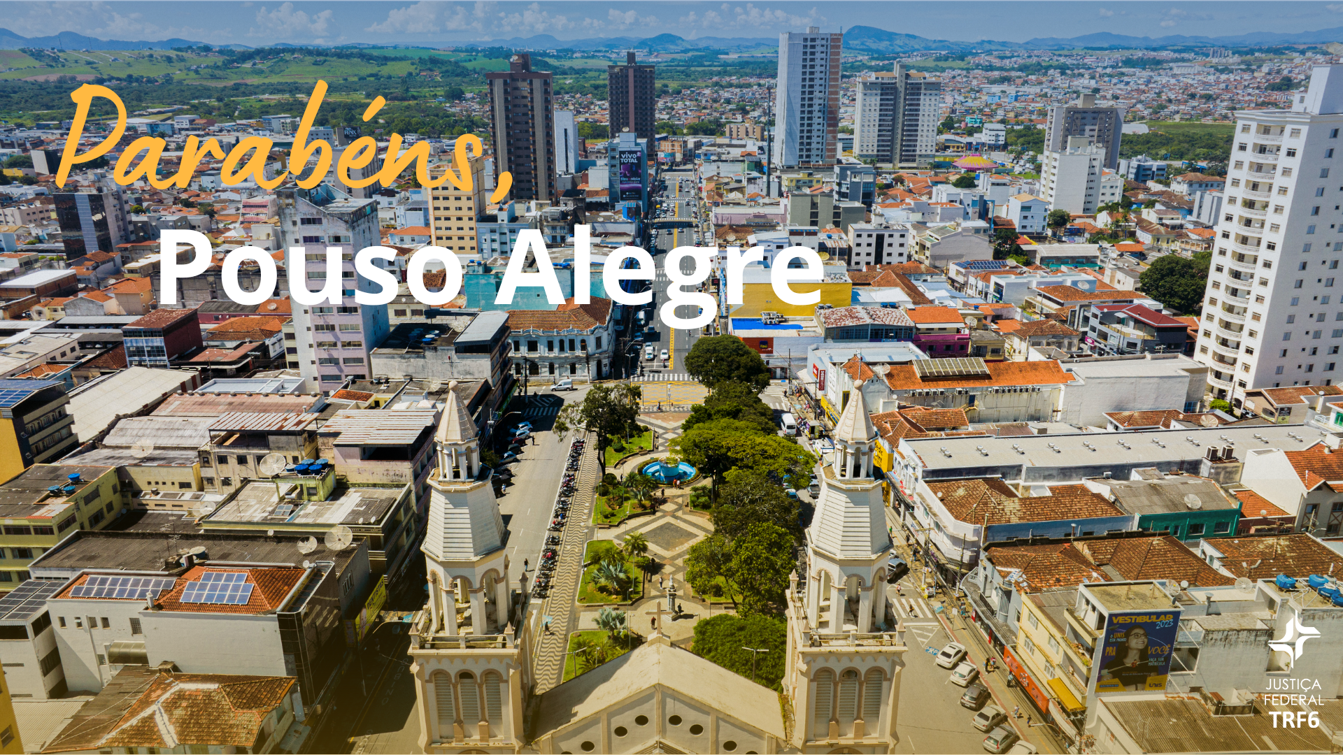 A imagem é uma fotografia aérea de uma paisagem urbana. No canto inferior direito, há um logotipo sutil da "JUSTIÇA FEDERAL TRF6". Sobre a foto, há uma mensagem de texto em destaque, com as palavras "Parabéns, Pouso Alegre", sendo "Parabéns" em amarelo cursivo e "Pouso Alegre" em branco.