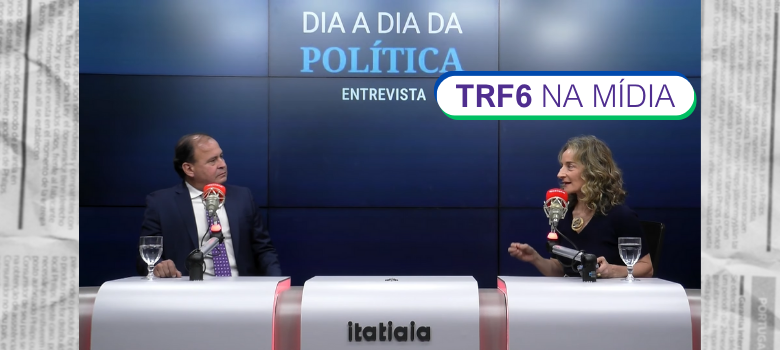A imagem é um frame de vídeo que mostra uma entrevista em um estúdio de televisão ou rádio. Um homem e uma mulher estão sentados, frente a frente, em uma mesa moderna de cor clara, com microfones e copos d'água. O homem veste um terno e gravata, e a mulher veste uma blusa escura. Ao fundo, um painel escuro exibe o título "DIA A DIA DA POLÍTICA" e a palavra "ENTREVISTA". No centro da tela, há um box gráfico com o texto "TRF6 NA MÍDIA". Na parte inferior da mesa, o nome "itatiaia" está em destaque. A imagem tem uma moldura externa que simula páginas de jornal amassadas.