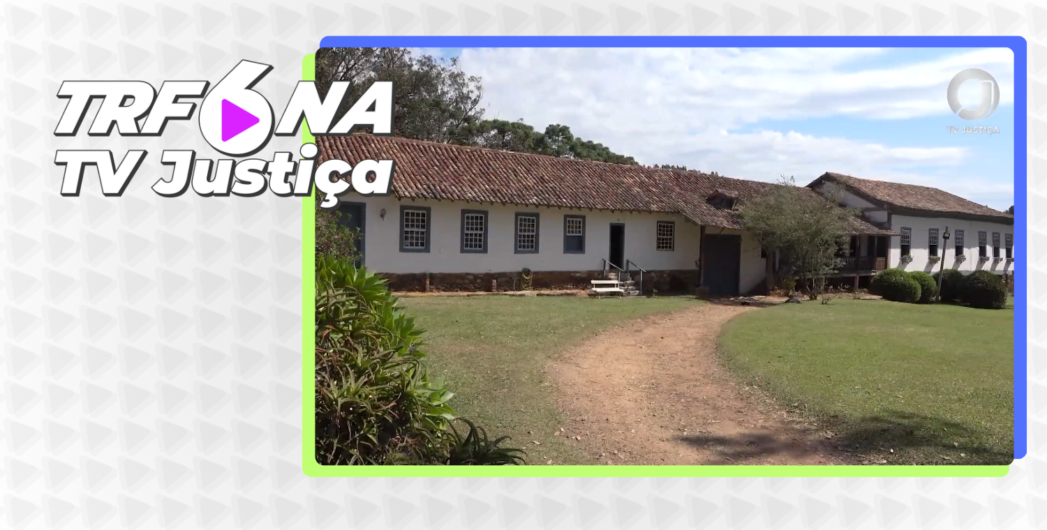 Esta imagem é um quadro do programa "TRF6 na TV Justiça", apresentando uma construção histórica em estilo colonial, com paredes brancas, janelas de moldura azul e telhado de barro. A edificação está cercada por uma área verde com um caminho de terra, destacando-se o logotipo do programa no canto superior esquerdo.